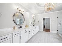 Bright bathroom with double vanity, stylish mirrors, white cabinets and a modern gold light fixture at 5945 Boulder Bluff Dr, Cumming, GA 30040