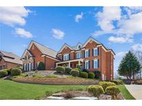 Beautiful brick home boasts an immaculately landscaped yard with lush greenery and vibrant bushes, creating a welcoming entrance at 5945 Boulder Bluff Dr, Cumming, GA 30040