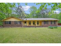 Charming brick home with a classic ranch-style design and mature trees in the landscaped front yard at 8540 Ridge Rd, Fairburn, GA 30213