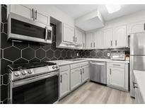 Modern kitchen features stainless steel appliances, light gray cabinets and a black hexagon tile backsplash at 2965 Pharr Court South Nw # 304, Atlanta, GA 30305