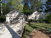 Charming single-story home featuring a two-car garage, well-manicured lawn, and mature trees providing ample shade at 1234 W Wylie Bridge Rd, Woodstock, GA 30188