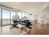 Bright living room with floor-to-ceiling windows, city views, modern decor, and a luxurious black sectional sofa at 1065 Peachtree Ne St # 2803, Atlanta, GA 30309
