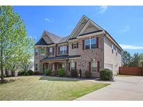 Charming two-story brick home with manicured lawn and vibrant landscaping in a Gathering-friendly neighborhood at 6150 Birchfield Trl, Cumming, GA 30041