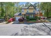 Charming yellow two-story home with well-maintained landscaping, mature trees, and an attached garage at 2008 Falcon Glen Ct, Alpharetta, GA 30022