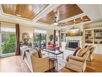 Spacious living room with a fireplace, wood floors, and custom wood tray ceilings at 320 Town Center Ave # U206B, Suwanee, GA 30024