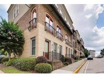 Modern townhome with brick and cream-colored facade, balconies, and manicured landscaping at 384 16Th Nw St # 1, Atlanta, GA 30363