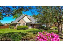 Charming brick home with well-manicured lawn, mature trees, and vibrant pink azaleas in the front yard at 925 Wynn Rd, Mcdonough, GA 30252