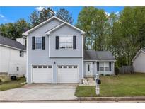 Charming two-story home with blue siding, a two-car garage, and a well-manicured lawn at 2565 Feywood Ct, Lithonia, GA 30058