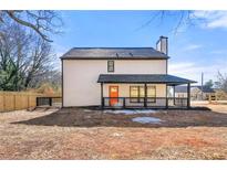 Side view of newly built home featuring a covered porch, black trim, orange front door, and manicured yard at 459 Orchard Dr, Stone Mountain, GA 30083