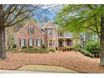 Charming two-story brick home with a beautifully landscaped front yard, accented by mature trees and a manicured lawn at 107 Grand Ave, Suwanee, GA 30024