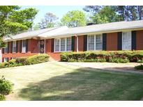 Charming brick home features a well-manicured lawn, lush shrubs, and black window shutters at 1568 Rainier Falls Ne Dr, Atlanta, GA 30329