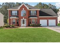 Charming two-story red brick home with a well-manicured lawn and a two-car garage at 192 Palisade Point Dr, Ellenwood, GA 30294