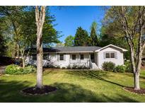 Charming white brick home featuring a well-manicured lawn and beautiful mature trees in a lovely front yard at 5132 Foxwood Ct, Atlanta, GA 30360