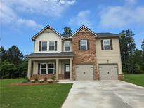 Two-story home featuring a brick and vinyl exterior, a two-car garage, and a well-manicured front lawn at 1594 Sungrown Way, Mcdonough, GA 30253