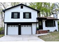 Charming two-story home boasts a white exterior with black accents and a two-car garage at 3867 Cherie Glen Rd, Snellville, GA 30039