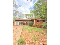 Charming one-story home with wood siding and a well-landscaped front yard surrounded by trees at 1445 Diplomat Dr, Riverdale, GA 30296