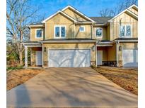 New construction townhome featuring a two-car garage and craftsman-style facade with light yellow siding and stone accents at 6860 Robinson St, Lithonia, GA 30058
