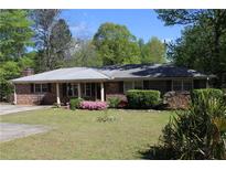 Charming brick home featuring a well-maintained lawn, inviting curb appeal, and vibrant flowering bushes at 1646 Hurt Sw Rd, Marietta, GA 30008