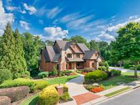 Beautiful brick home features a lush landscaped front yard, winding walkway, and mature trees at 2740 Drayton Hall Dr, Buford, GA 30519