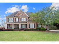 Charming brick home featuring a manicured lawn, mature landscaping, and inviting curb appeal at 2032 Grovewood Ct, Cumming, GA 30041