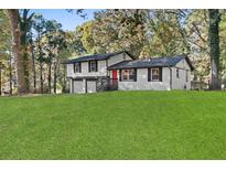 Charming two-story home boasts a white exterior, black trim, inviting red door, and a spacious green lawn at 1971 Westley Dr, Riverdale, GA 30296