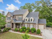 Stunning two-story brick home with a manicured lawn and lush landscaping at 626 Oakbourne Way, Woodstock, GA 30188