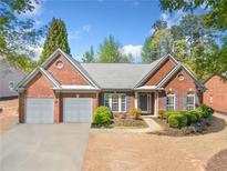 Charming brick home featuring a two-car garage, landscaped yard, and inviting front entrance at 1330 Badingham Dr, Cumming, GA 30041