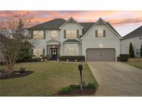 Charming two-story home with a well-manicured lawn, two-car garage, and beautiful landscaping at 6060 Country Lake Rd, Cumming, GA 30041