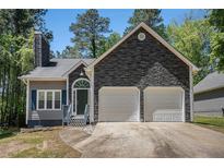 Charming home featuring a two-car garage, stone accents, and a well-manicured front yard at 3076 Nectar Dr, Powder Springs, GA 30127