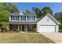 Charming two-story home with a brick facade and attached two car garage and a manicured front yard at 2181 Poplar Grove Ct, Snellville, GA 30078