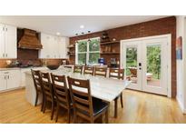 Bright kitchen features a long island with a stone countertop, white cabinetry, stainless appliances, and brick accent wall at 6765 Creek View Ln, Cumming, GA 30041