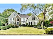 Stately home featuring a well-manicured lawn and a combination of stone and siding accents at 10355 Oxford Mill Cir, Johns Creek, GA 30022