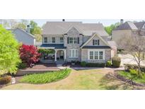 Beautiful two-story home featuring brick facade, covered front porch, and manicured landscaping at 147 Johnston Farm Ln, Woodstock, GA 30188