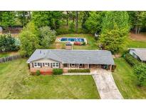 Expansive yard with brick home, driveway, and in-ground pool surrounded by mature trees at 690 Manor Ridge Sw Dr, Mableton, GA 30126