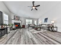Spacious living room boasts a fireplace, ceiling fan and wood flooring at 305 Nobleman Way, Canton, GA 30114