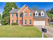 Charming two-story brick home featuring a well-manicured lawn, a red front door, and an attached two-car garage at 210 Chandler Ct, Sugar Hill, GA 30518