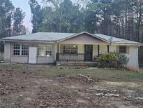 Modest single-story brick home with mature trees and a covered front porch at , Stockbridge, GA 30281
