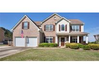 Charming two-story brick home featuring a well-manicured lawn, covered porch, and a two-car garage at 209 Crestmont Way, Canton, GA 30114