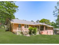 Expansive backyard featuring a brick house, wooden deck with stairs, and well-maintained lawn surrounded by mature trees at 4307 Smithsonia Ct, Tucker, GA 30084