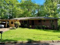 Charming brick home featuring a lush green lawn, carport and classic design at 2292 1St Ne Ave, Atlanta, GA 30317
