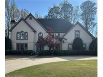 Charming home with manicured lawn, mature trees, and a traditional facade with beautiful windows at 9290 Prestwick Club Dr, Johns Creek, GA 30097