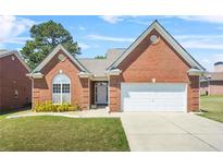 Charming brick home with well-manicured lawn, arched window, and attached two-car garage at 8495 Spivey Village Way, Jonesboro, GA 30236
