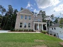 New two-story brick home boasts a manicured lawn and welcoming covered porch at 4520 Ajo Walk, Atlanta, GA 30331