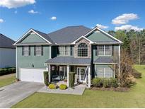 Charming two-story home with green siding, a well-manicured lawn, and an attached two-car garage at 419 Farmwood Way, Canton, GA 30115