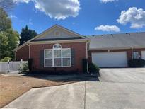 Charming red brick home with a two-car garage and white picket fence, and well maintained lawn and garden at 119 Holiday Rd # 704, Buford, GA 30518