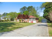 Charming brick home with a well-manicured lawn, a long driveway, and a detached garage at 566 Huff St, Lawrenceville, GA 30046