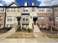 Charming townhome featuring brick facade, dormer windows and well-manicured landscaping at 4487 Kerrington Ave, Sugar Hill, GA 30518