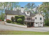 Two story home with a two-car garage, white siding, black shutters and a rear wooden deck and lush landscaped yard at 2972 Nw Stilesboro Nw Rd, Kennesaw, GA 30152