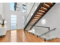 Bright foyer features wood floors, stairs with glass railings, and a modern light fixture at 820 Moores Mill Nw Rd, Atlanta, GA 30327