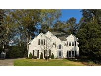 Charming white brick two-story home with manicured lawn and mature trees, creating a serene and inviting curb appeal at 2270 Fenwick Pointe Sw, Marietta, GA 30064